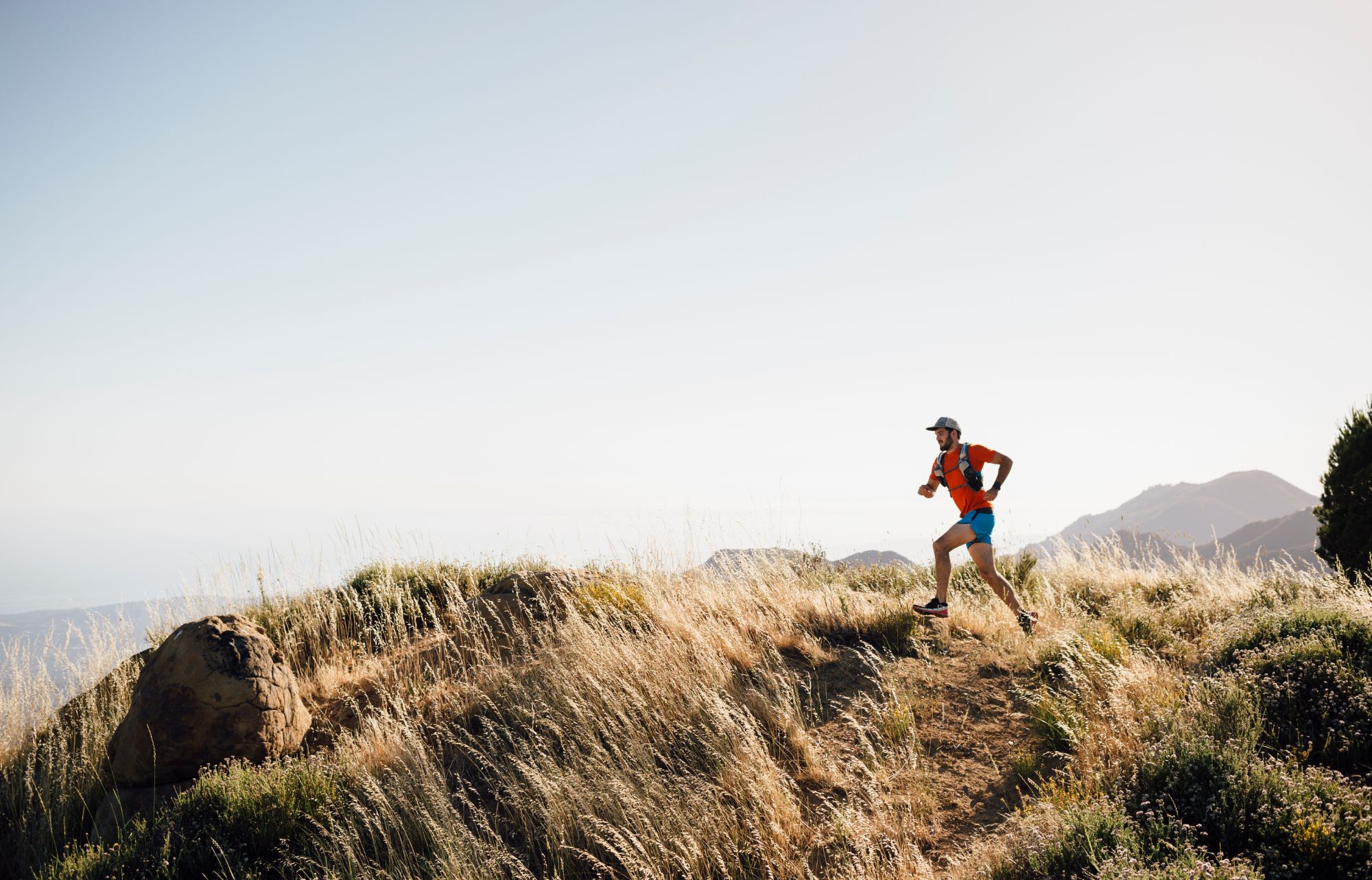 A trail runner on a ridgeline at sunrise